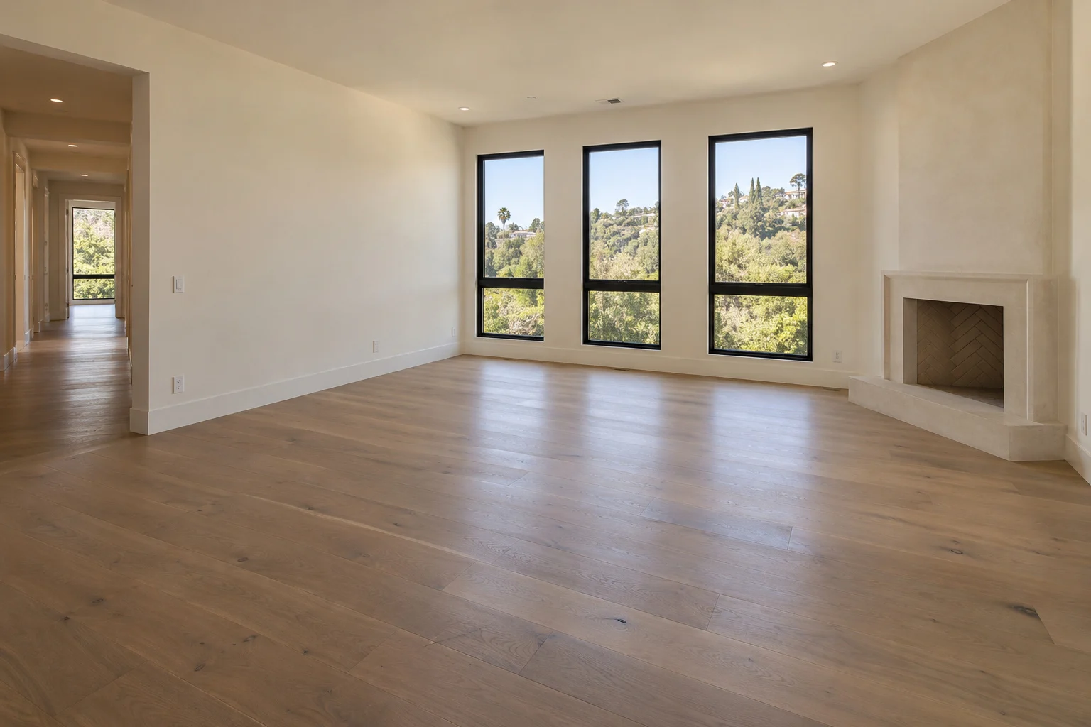 Fictional empty living room with oak floors, three tall windows and a stone fireplace